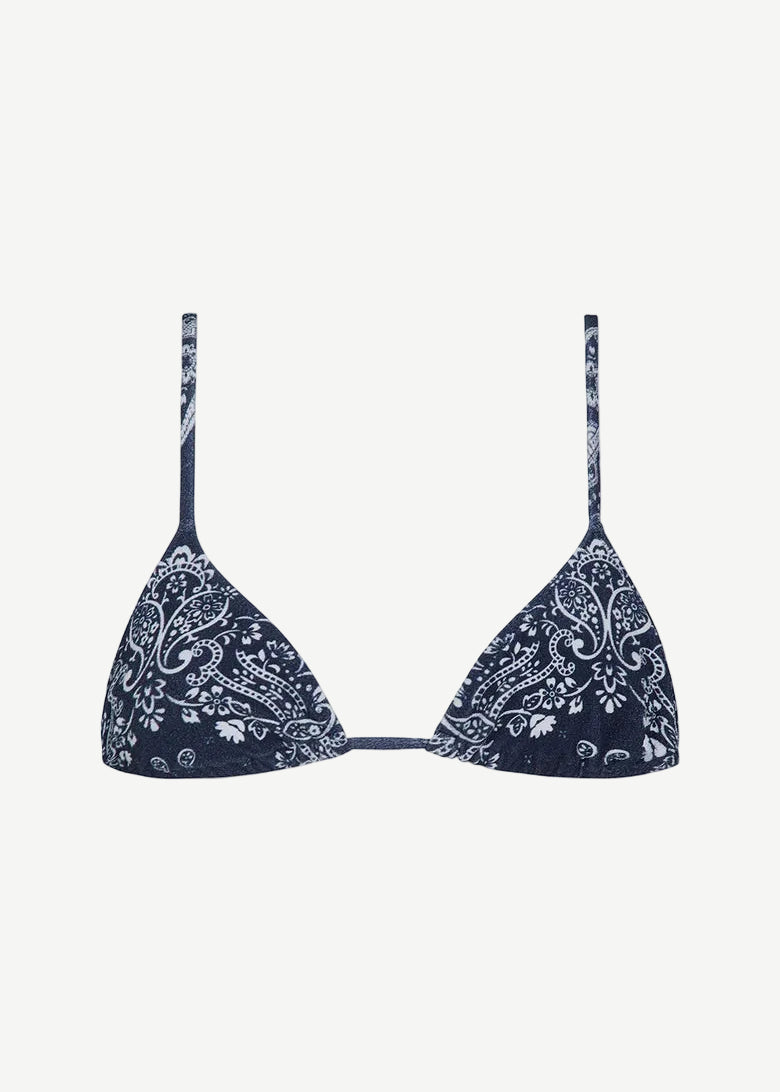 The Equator Top is a navy blue triangle bikini top with thin straps and a white paisley floral pattern. Made from ECONYL regenerated nylon, this adjustable bikini top offers a simple, minimalistic design for an effortlessly chic look.
