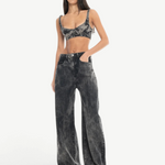 A woman with long dark hair stands with her hands in her pockets against a plain white background, wearing Acid Wash Boyfriend Jeans and a matching grey acid-wash crop top.