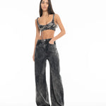 A woman with long dark hair stands with her hands in her pockets against a plain white background, wearing Acid Wash Boyfriend Jeans and a matching grey acid-wash crop top.