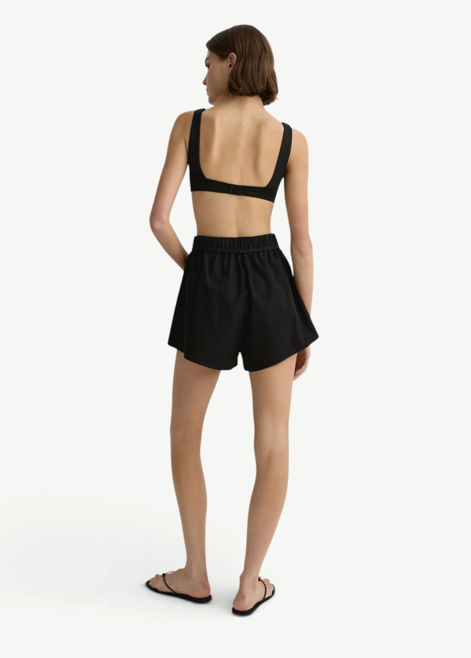 Model wearing KABE SHOP INC black Kyoto mini shorts in Japanese dry cotton with an elastic waist and tie belt, back view