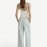 A person seen from behind wears a white tank top with blue trim and white Finn Pant drawstring pants with blue vertical stripes.
