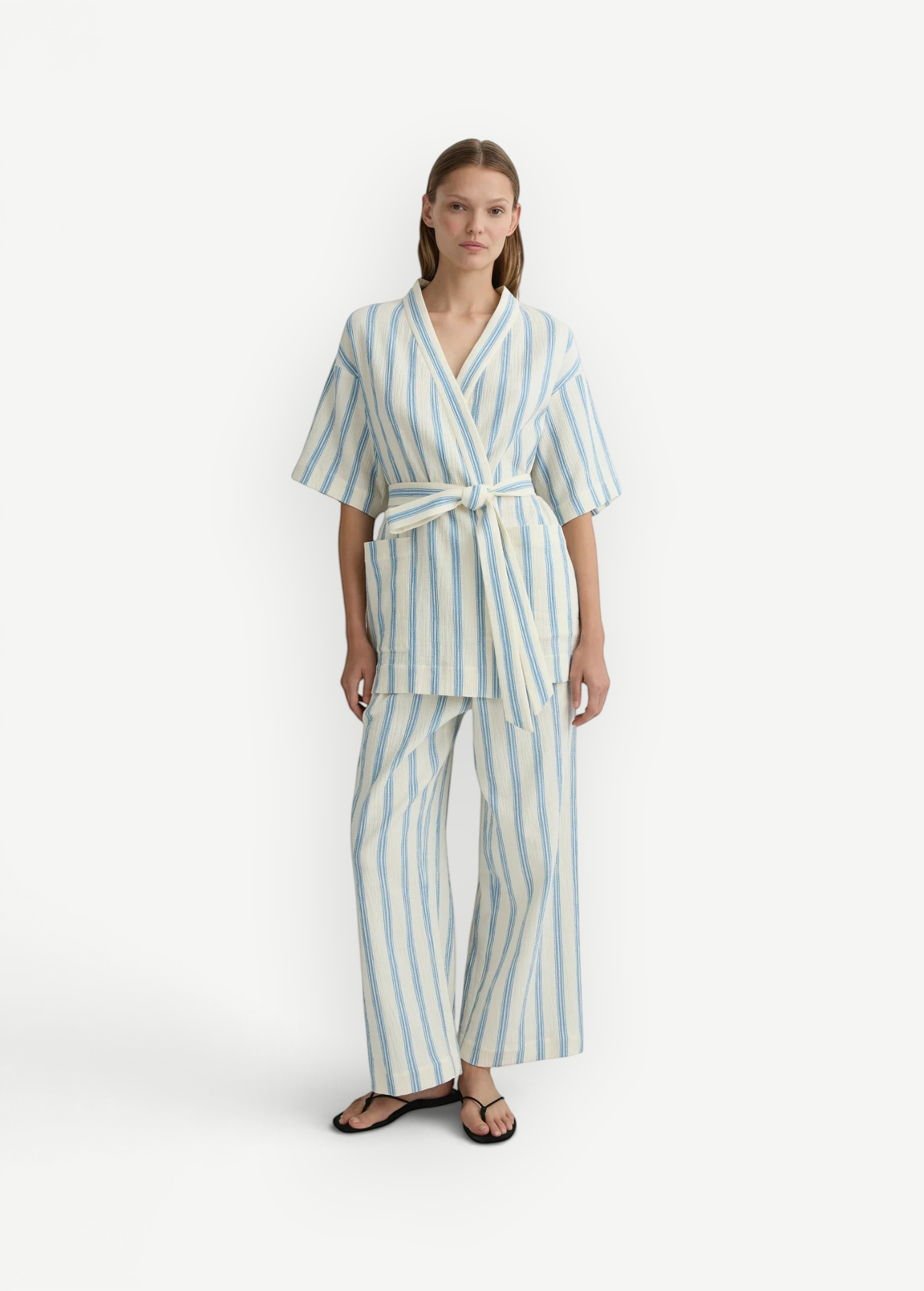 Model wearing KABE SHOP INC Finn wrap tunic and matching trousers in cream and blue striped lightweight fabric