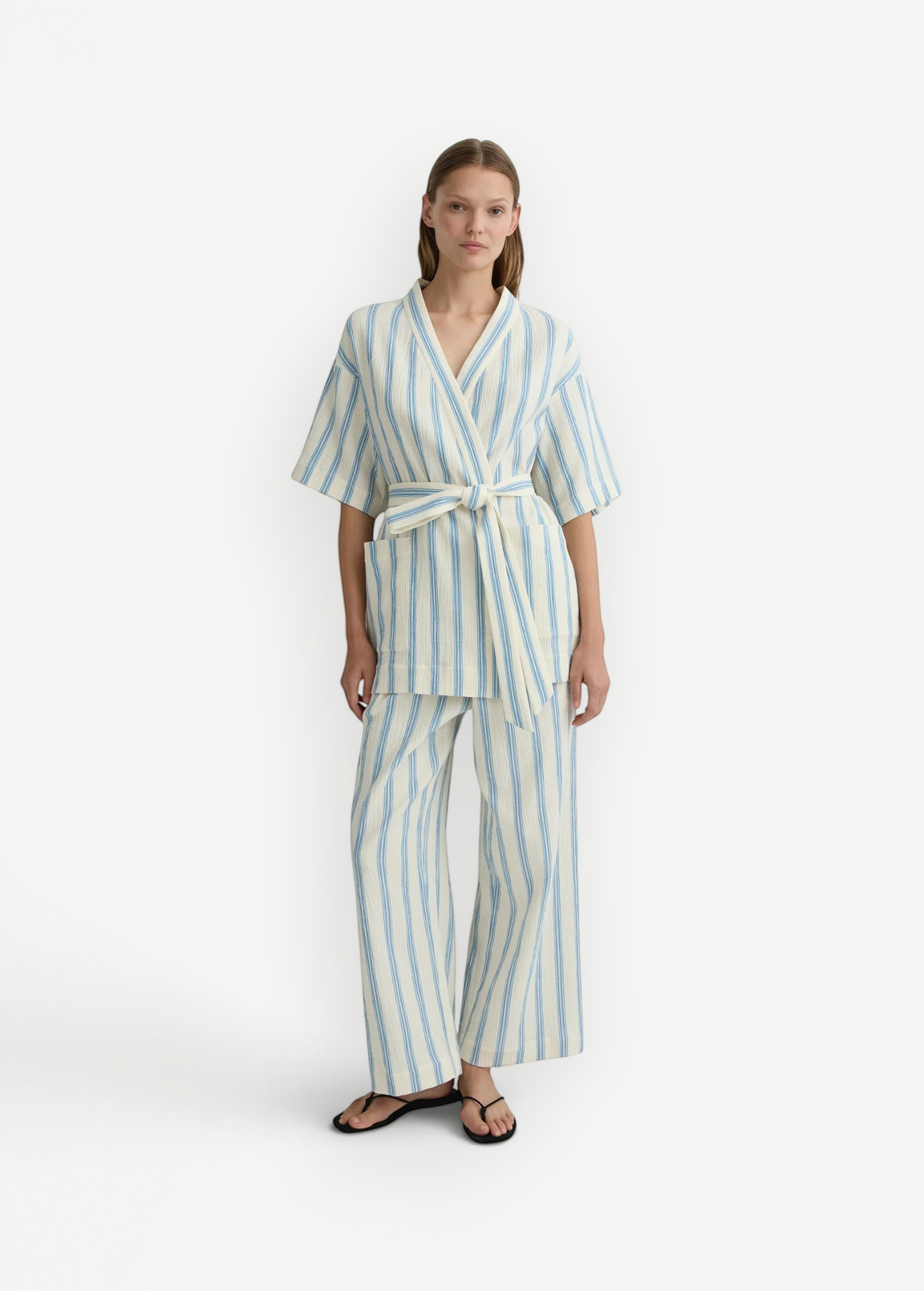 Model wearing KABE SHOP INC Finn wrap tunic and matching trousers in cream and blue striped lightweight fabric