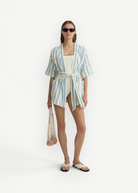 Model wearing KABE SHOP INC Finn wrap tunic in white and blue stripe with a matching swimsuit and mesh bag