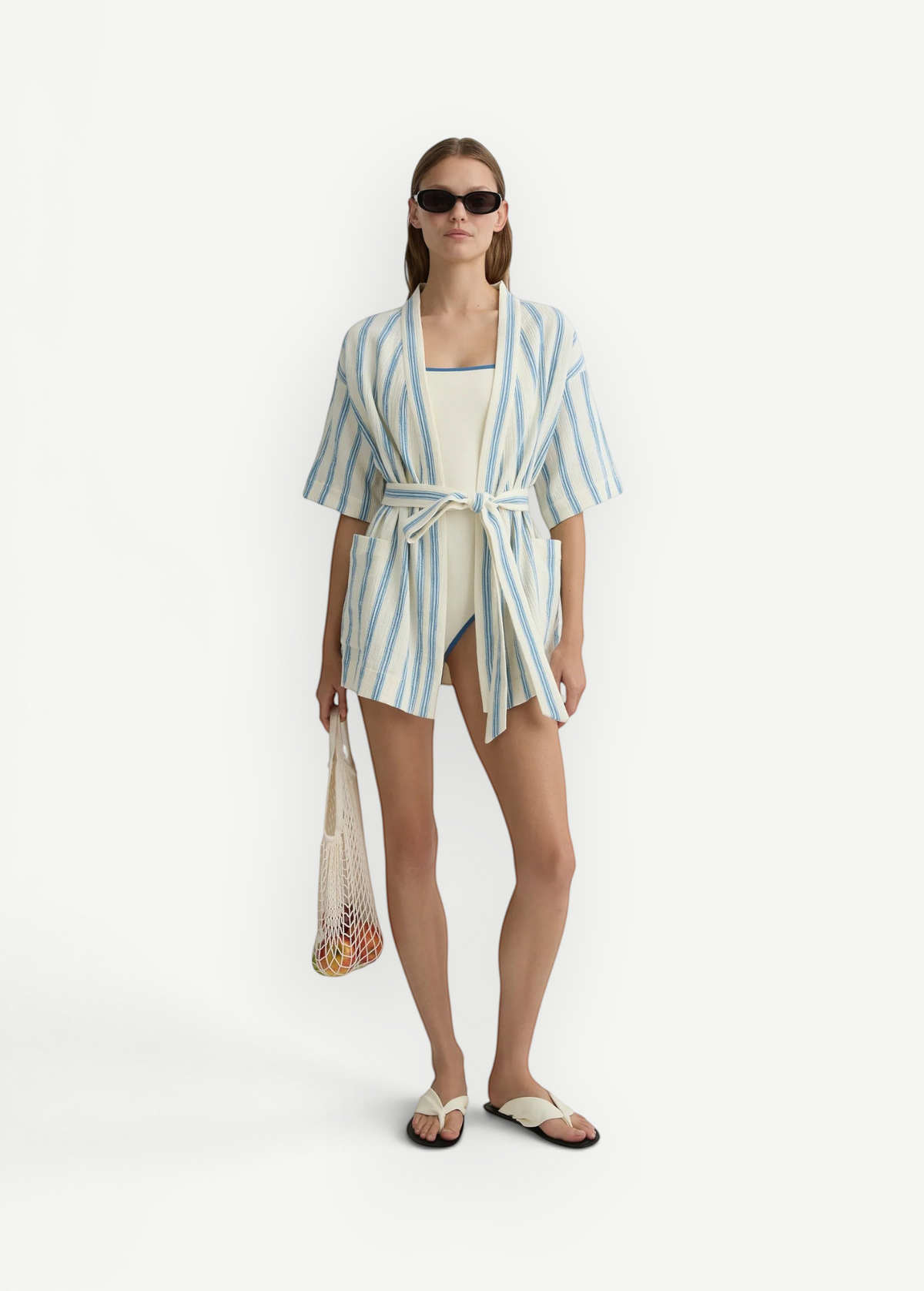 Model wearing KABE SHOP INC Finn wrap tunic in white and blue stripe with a matching swimsuit and mesh bag