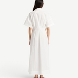 Back view of a woman wearing a white KABE SHOP INC Kyoto shirt dress with short sleeves and a 7/8 length hem.