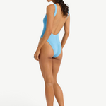 Model wearing KABE SHOP INC Mara blue textured one-piece swimsuit with a low scoop back and high-cut leg