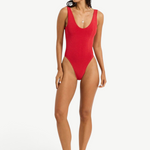 Model wearing KABE SHOP INC Mara red one-piece swimsuit with V-neckline and high-cut leg on a white background