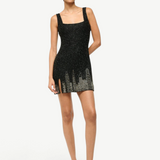 A woman in a black mini dress with a crystal city skyline motif, styled with a refined silhouette in light-colored Brigitte Heel mules.