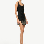 A person wears a black sleeveless mini dress with silver embellishments and open-toe Brigitte Heel mules that offer a refined silhouette.