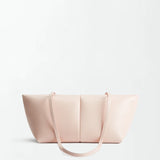 The Boulevard Sling Bag, crafted from light pink nappa leather, features two thin shoulder straps and is set against a plain white background. Its minimalist design showcases smooth leather with subtle stitching and a rectangular silhouette that curves elegantly at the sides.