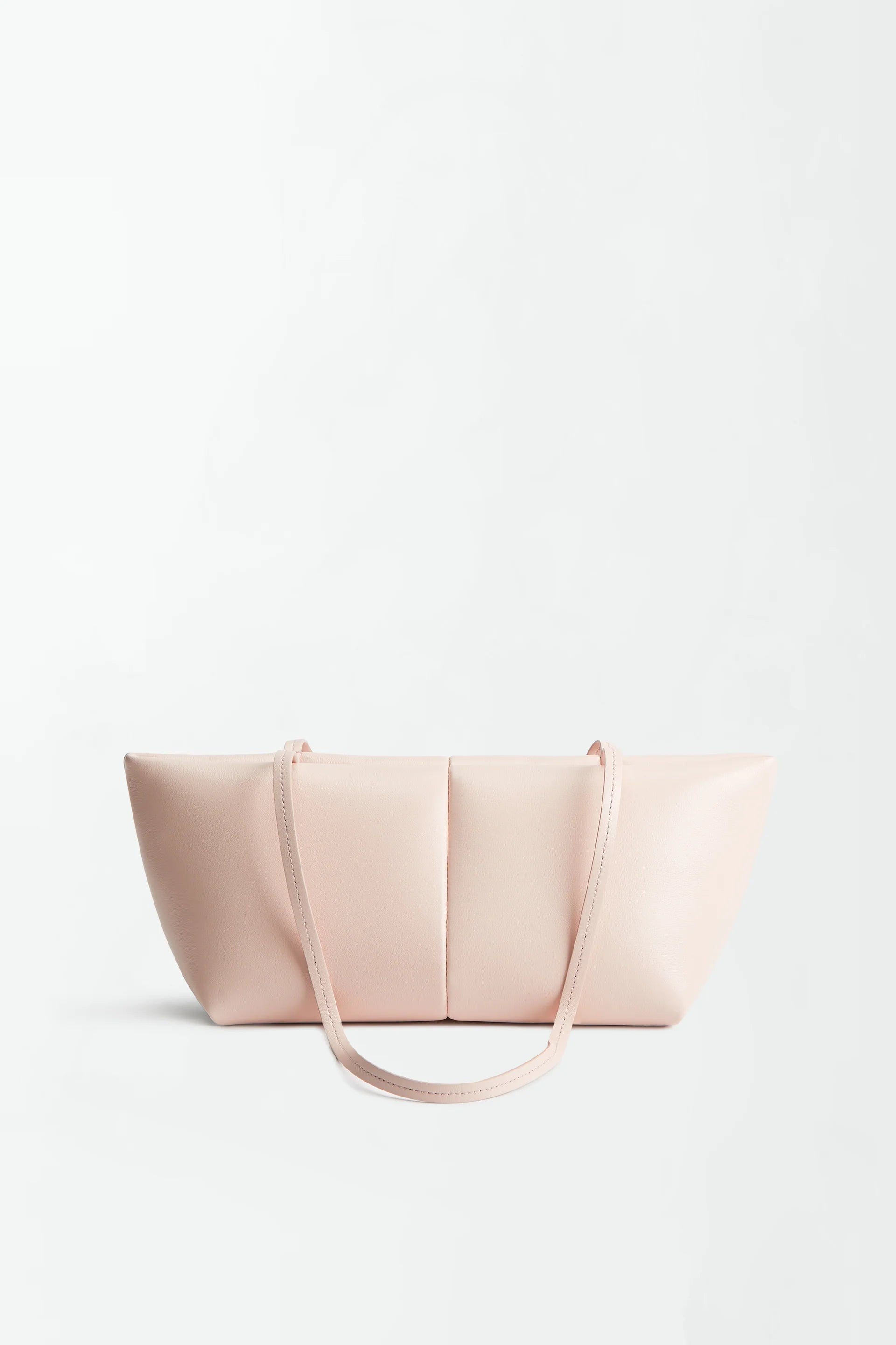 The Boulevard Sling Bag, crafted from light pink nappa leather, features two thin shoulder straps and is set against a plain white background. Its minimalist design showcases smooth leather with subtle stitching and a rectangular silhouette that curves elegantly at the sides.