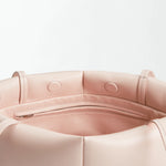 Close-up of the interior of the Boulevard Sling Bag in light pink nappa leather, featuring a zippered pocket and stitched details on soft, matte material.