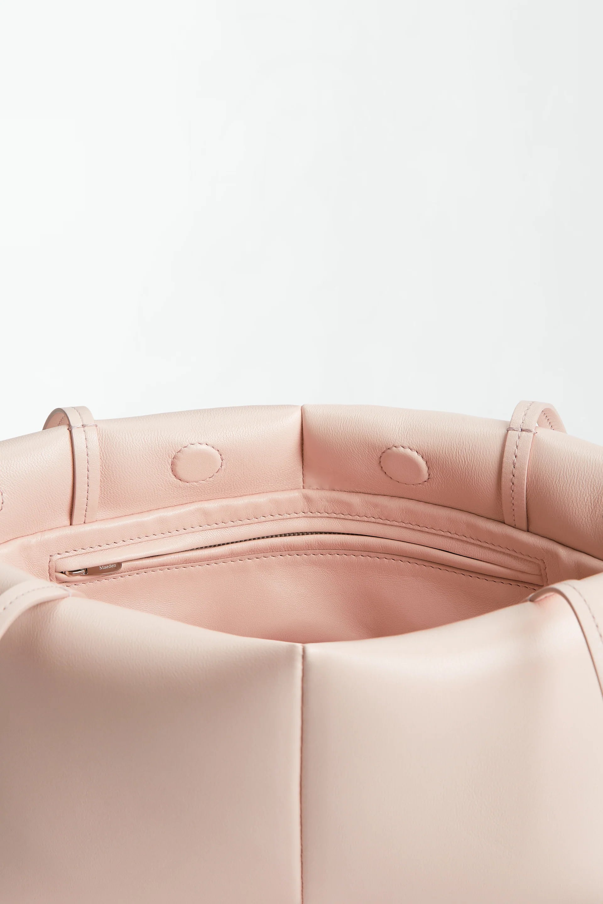 Close-up of the interior of the Boulevard Sling Bag in light pink nappa leather, featuring a zippered pocket and stitched details on soft, matte material.