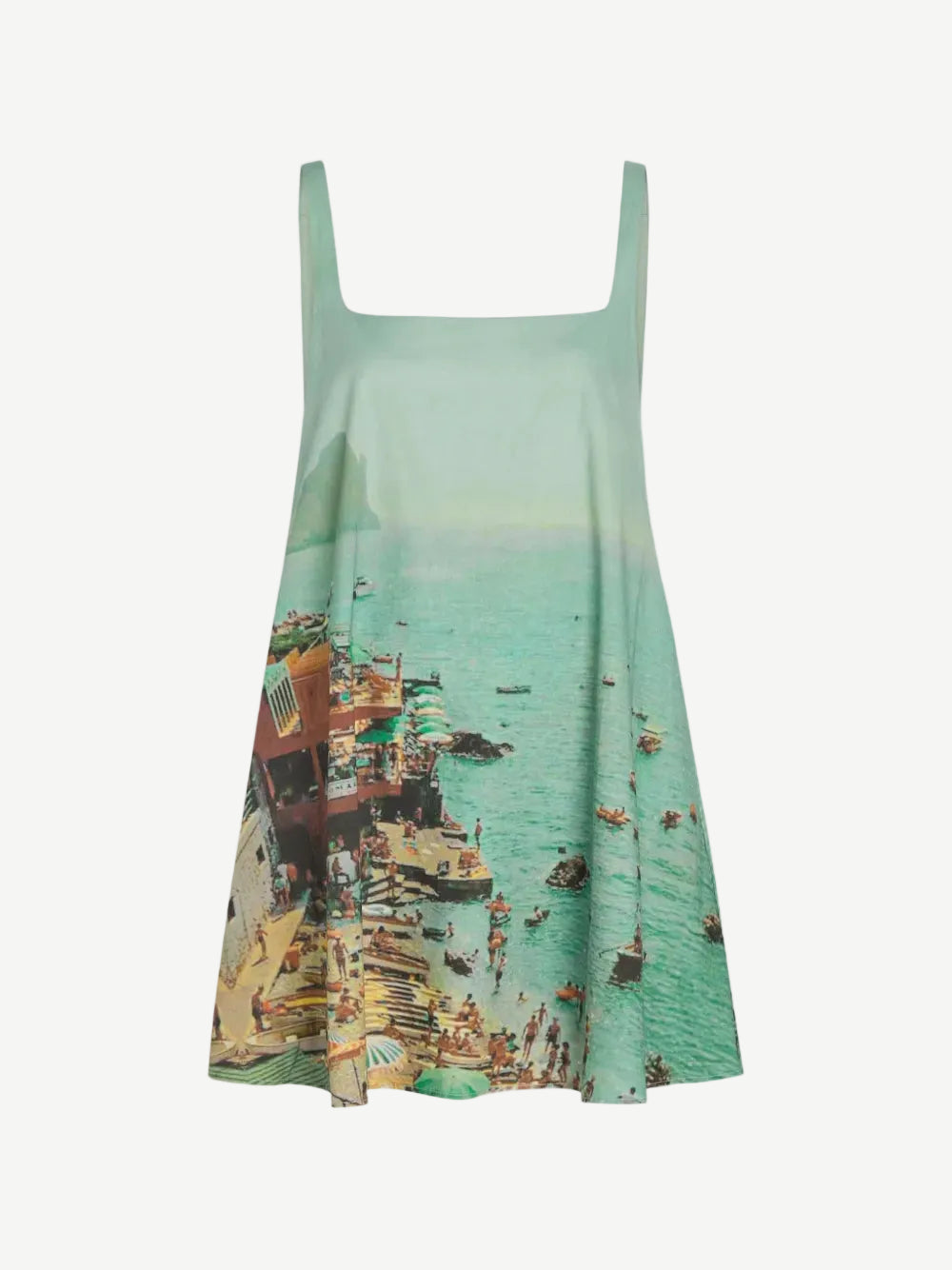 The Brio Dress is a square-neck mini dress featuring a print of a crowded beach and coastal town, designed as a versatile warm-weather essential.