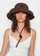 KABE SHOP INC brown crochet hat bag with a leather chin strap worn by a woman with curly hair