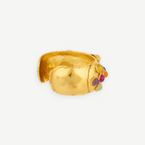 Introducing the Theodora Cuff: a wide, handcrafted gold cuff bracelet with a textured finish, adorned on one side with an eye-catching arrangement of vibrant round stones in purple, orange, yellow, and green. Effortlessly wearable, this statement piece is perfect for anyone who loves unique jewelry.