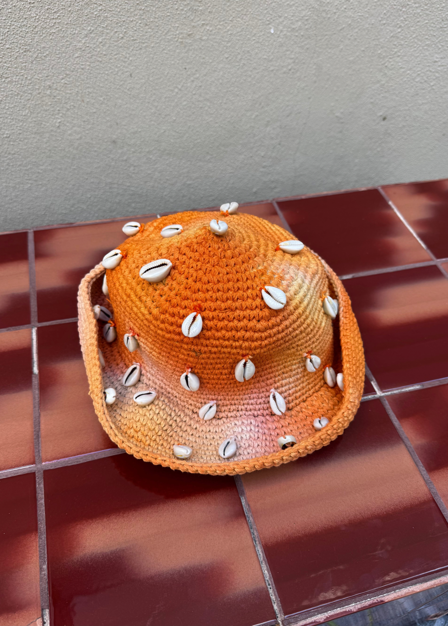 KABE SHOP INC handmade crochet tie-dye bucket hat in orange with white cowrie shell embellishments