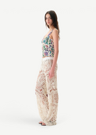 Model wearing KABE SHOP INC Cali Top with floral pattern and wide straps paired with cream lace trousers