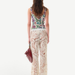 KABE SHOP INC Cali Top featuring a colorful floral print, worn with cream crochet lace trousers and a maroon bag.
