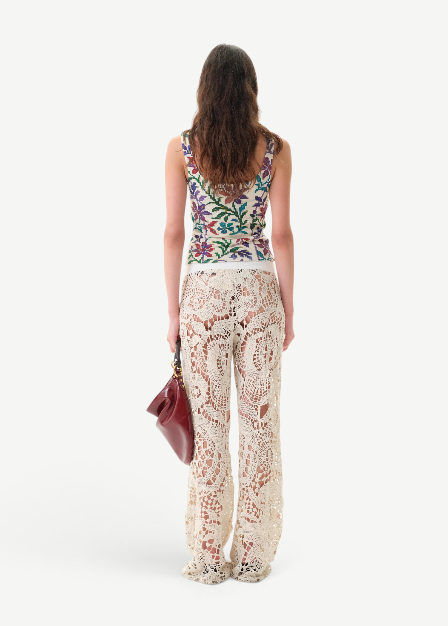 KABE SHOP INC Cali Top featuring a colorful floral print, worn with cream crochet lace trousers and a maroon bag.