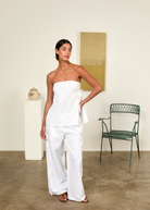 Model wearing KABE SHOP INC white strapless Sebastian Top with floral embroidery and side tie detail