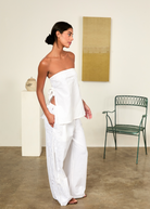 Model wearing KABE SHOP INC white strapless Sebastian Top with floral embroidery and side tie details