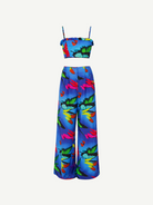 The Alma Set is a colorful tropical print two-piece linen ensemble featuring a cropped spaghetti strap top and wide-leg high-waisted pants. Perfect for versatile styling, this standout outfit is beautifully showcased against a plain white background.