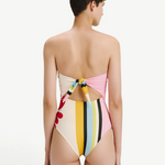 Model wearing KABE SHOP INC Ulla one piece swimsuit with a multi-colored striped pattern and back tie detail.