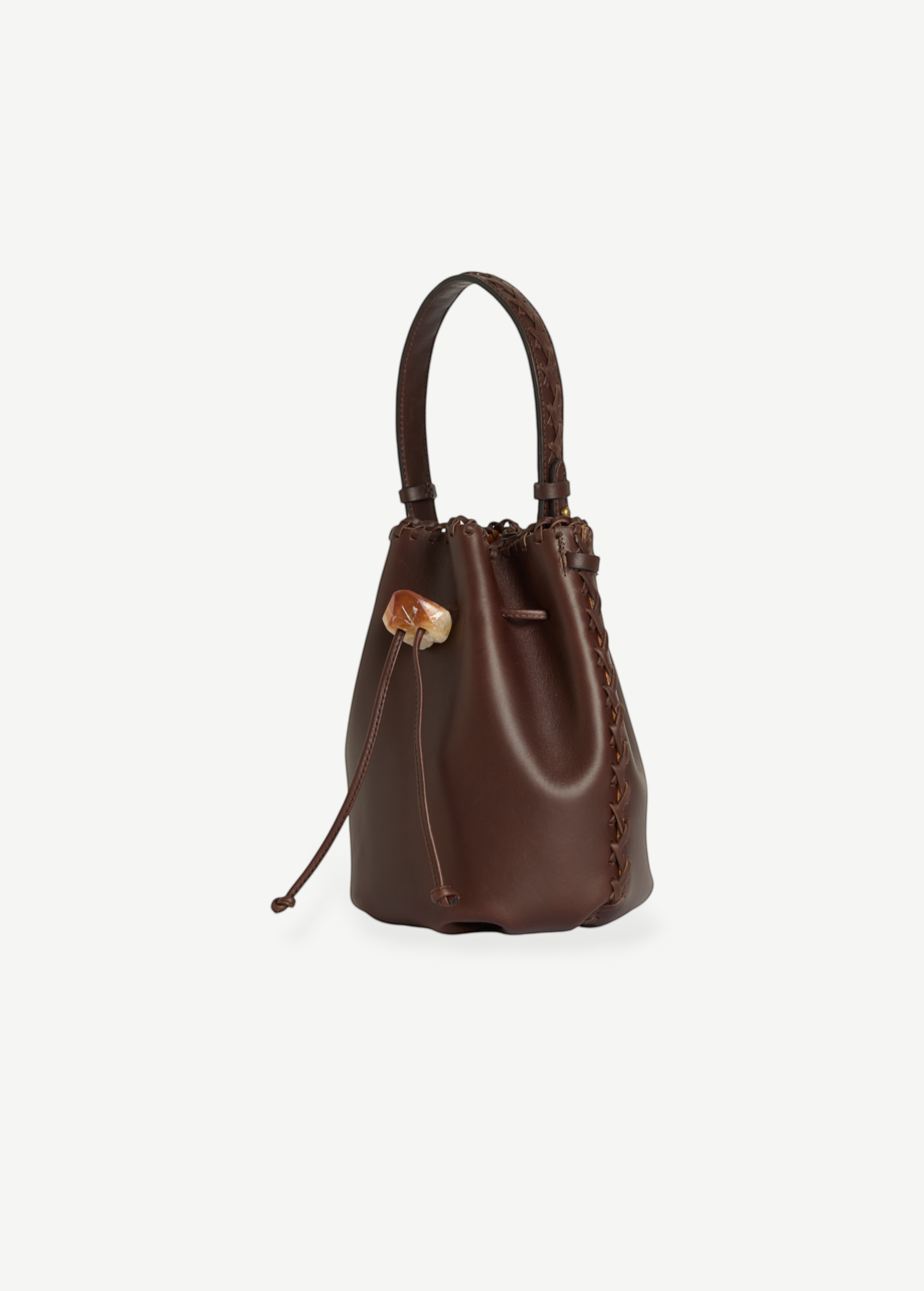 KABE SHOP INC Nirmala Vacchetta bucket bag in dark brown leather with braided side details and crystal drawstring