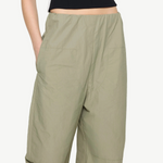 Sage green high-waisted Cocoon Trackpant with side pockets and vertical side stripes, offering a relaxed, utilitarian fit.
