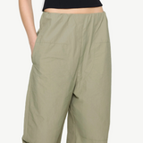 Sage green high-waisted Cocoon Trackpant with side pockets and vertical side stripes, offering a relaxed, utilitarian fit.