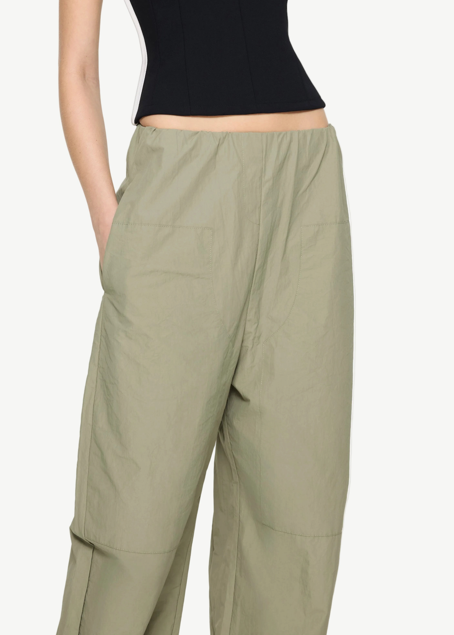 Sage green high-waisted Cocoon Trackpant with side pockets and vertical side stripes, offering a relaxed, utilitarian fit.