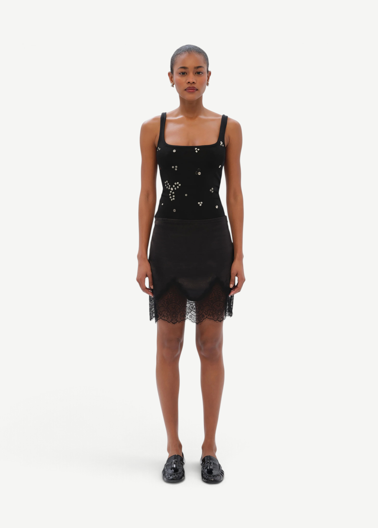 Model wearing KABE SHOP INC Dasne black bodysuit with square neckline and silver stud embellishments