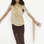 A person wears a pale yellow Menorca top in a sleeveless, draped viscose georgette with a long scarf detail and a floor-length brown lace skirt.