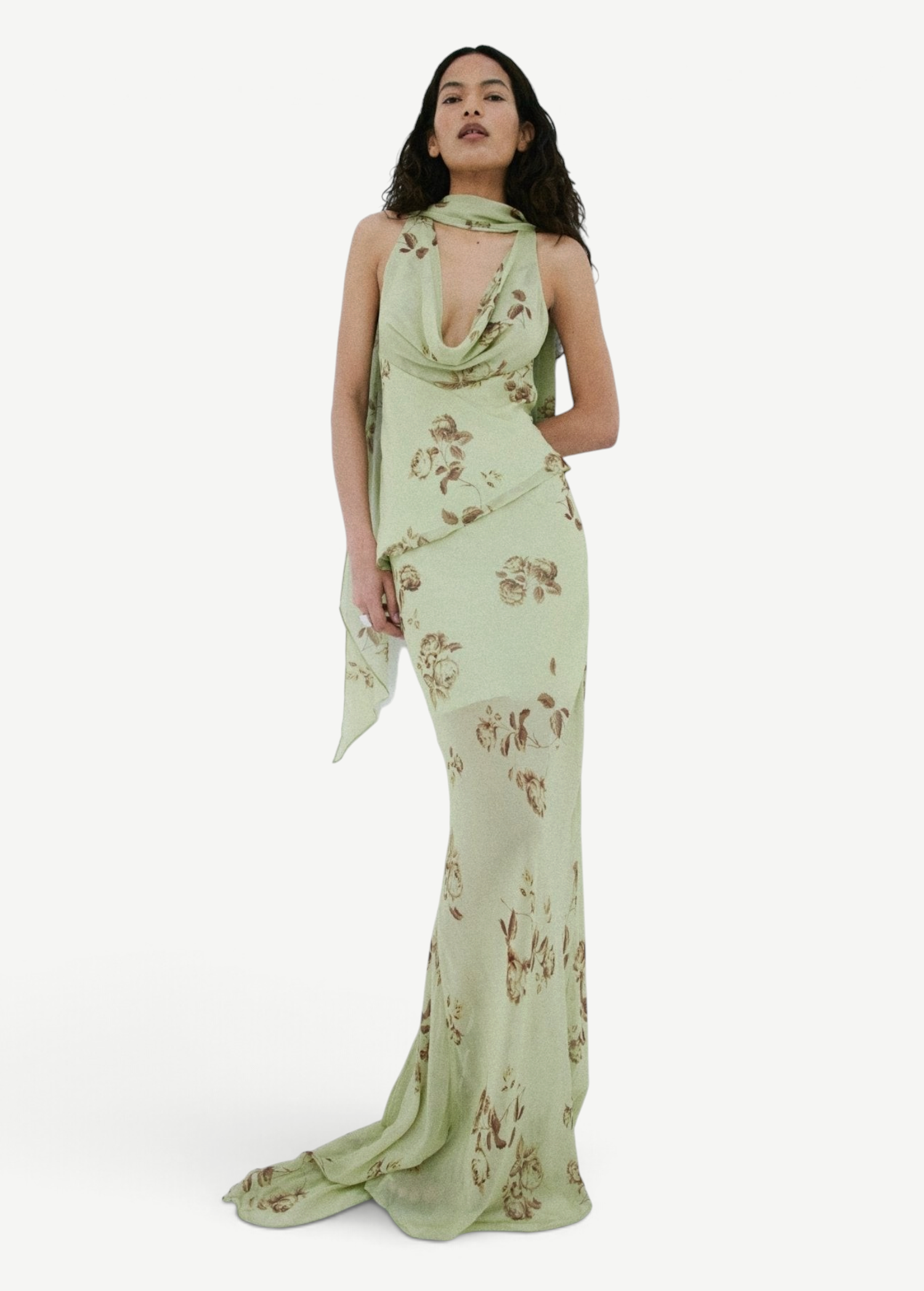 A person wears the sage green, floor-length georgette Diosa Skirt with a cowl neckline, brown floral print, and an asymmetric hem.
