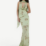 A person wears the sage green, floor-length georgette Diosa Skirt with a cowl neckline, brown floral print, and an asymmetric hem.