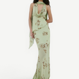 A person wears the sage green, floor-length georgette Diosa Skirt with a cowl neckline, brown floral print, and an asymmetric hem.