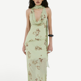 A model wears the Diosa Skirt, a light green midi-length dress with a cowl neckline, an asymmetric hem, and a brown floral print.