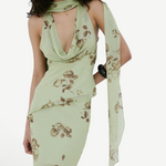 A person wears a pale green, floral-print bohemian style Diosa Top with a matching scarf and an asymmetrical hemline.
