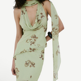 A person wears a pale green, floral-print bohemian style Diosa Top with a matching scarf and an asymmetrical hemline.