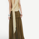 A person wearing a pale yellow, sleeveless, open-back top tucked into an Agapito Skirt, a long, taupe chiffon skirt with a gathered waistband that creates an elongated silhouette.