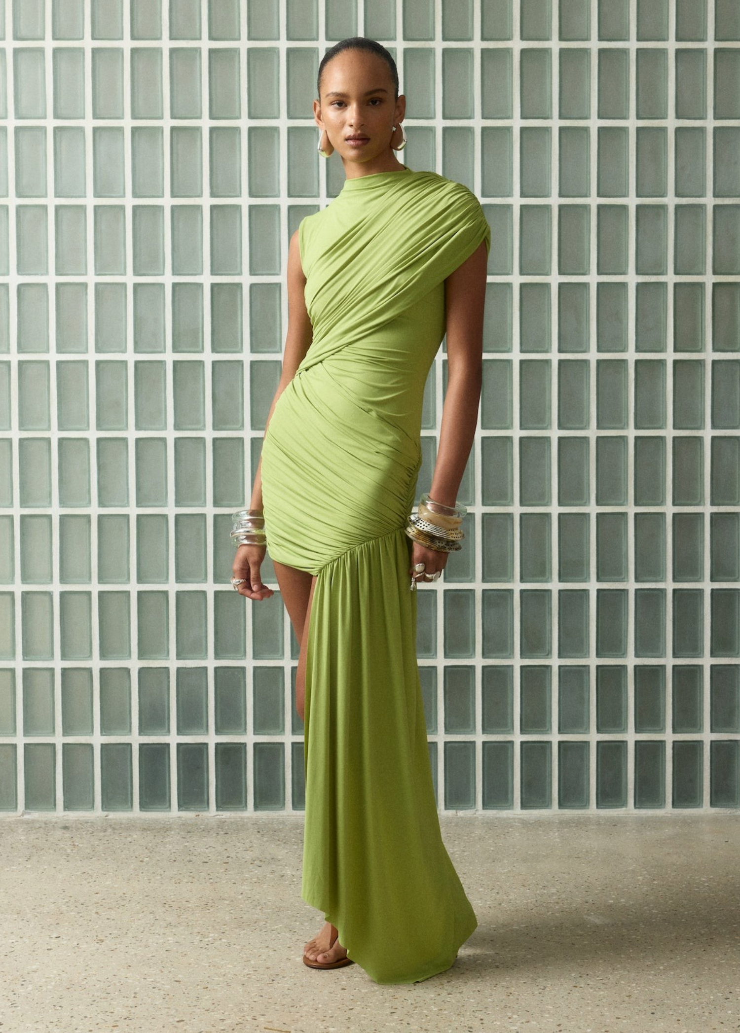Model wearing a lime green KABE SHOP INC Ravenna mini dress with sculpted draping and an asymmetric sash skirt.