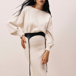 Model wearing KABE SHOP INC Laisse black Italian calfskin garter belt over a cream long-sleeve dress