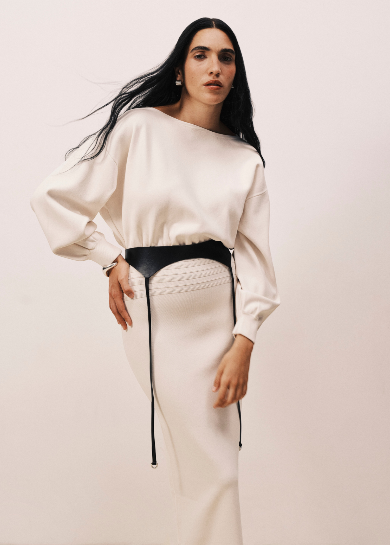Model wearing KABE SHOP INC Laisse black Italian calfskin garter belt over a cream long-sleeve dress