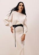 Model wearing KABE SHOP INC Laisse black Italian calfskin garter belt over a cream long-sleeve dress