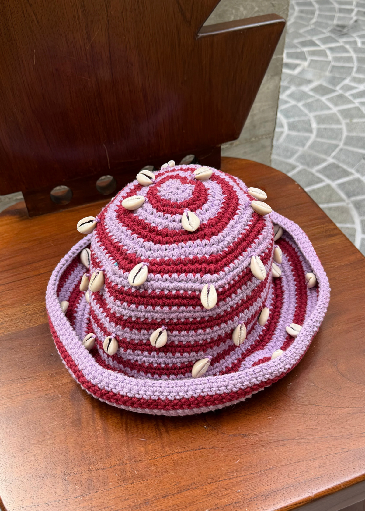KABE SHOP INC handmade crochet bucket hat in pink and maroon stripes, decorated with natural white sea shells.