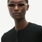 KABE SHOP INC Valentina oval sunglasses in translucent blush acetate worn by a model in a black cardigan