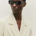Model wearing KABE SHOP INC Vivian black rectangular acetate sunglasses with a cream wool blazer