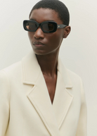 Model wearing KABE SHOP INC Vivian black rectangular acetate sunglasses with a cream wool blazer